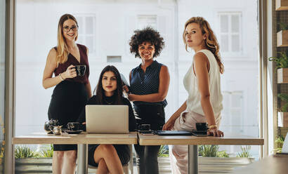 Portrait of four successful young businesswomen together in office. Group of multi-ethnic businesswomen looking at camera. - JLPSF16773