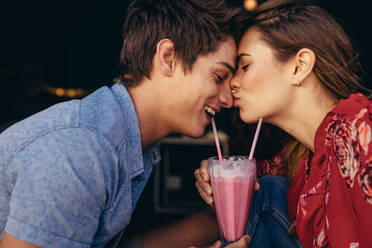 Frau küsst ihren Freund auf die Nase, während sie mit ihm in einem Restaurant verabredet ist. Paar in einem Restaurant in romantischer Stimmung bei einem Milchshake. - JLPSF16791