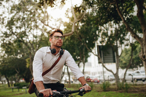 Gesundheitsbewusster Mann, der mit dem Fahrrad ins Büro fährt. Mann mit Bürotasche auf dem Fahrrad. - JLPSF16815