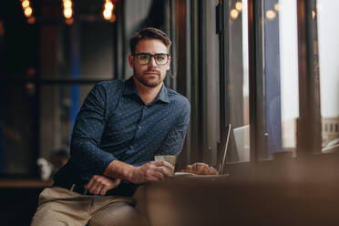 Freiberufler sitzt in einem Restaurant mit Essen auf dem Tisch. Geschäftsmann entspannt in einem Café sitzen mit Essen vor, während die Arbeit am Laptop. - JLPSF16855