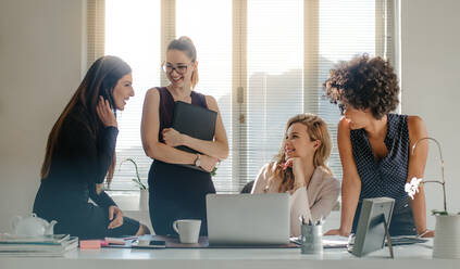 Gruppe multiethnischer Geschäftsfrauen bei einer lockeren Diskussion im Büro. Gruppe von vier Frauen, die sich während der Arbeitspause im Büro unterhalten. - JLPSF16917