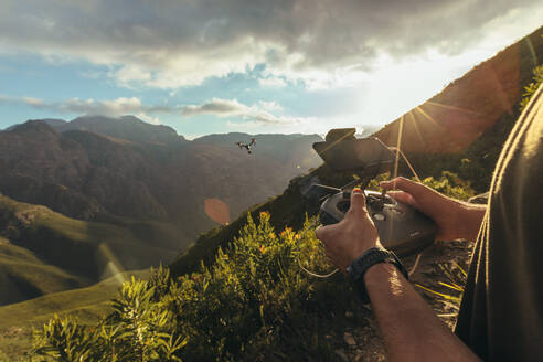 Wanderer, der eine Drohne über einem Naturschutzgebiet fliegt und an einem sonnigen Tag Fotos macht. Nahaufnahme eines Mannes, der eine Quadcopter-Drohne mit einer Fernbedienung steuert. - JLPSF16959