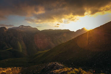 Schöner Blick auf den Sonnenuntergang im Naturschutzgebiet Jonkershoek. Sonnenuntergang über den Bergen bei bewölktem Himmel. - JLPSF16966