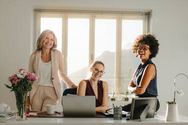 Three laughing businesswomen in casuals looking at camera. Group of successful businesswomen in office. - JLPSF16970