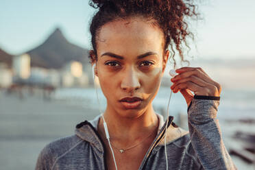 Nahaufnahme einer Sportlerin mit Kopfhörern im Freien, die beim Training Musik hört. - JLPSF16971