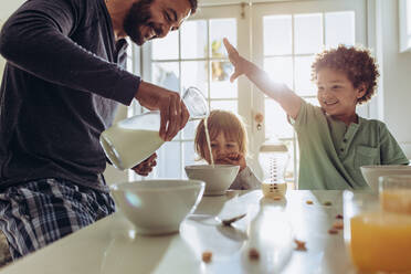 Father making breakfast for his kids at home. Man having fun preparing breakfast at home with his kids. - JLPSF17013