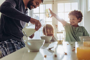 Ein Vater, der zu Hause das Frühstück für seine Kinder zubereitet. Ein Mann, der mit seinen Kindern zu Hause das Frühstück zubereitet. - JLPSF17013