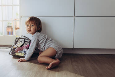Kid crawling on floor playing with a bag containing cosmetics. Little kid sitting on floor playing alone. - JLPSF17019
