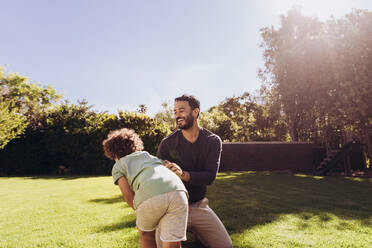 Father and son playing in the park on a sunny day. Smiling man spending time with his son outdoors - JLPSF17036