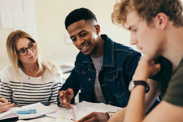 Afrikanischer Junge beim Lernen mit Klassenkameraden. Gruppe multiethnischer Studenten bei der Arbeit an College-Aufgaben auf dem Campus. - JLPSF17129