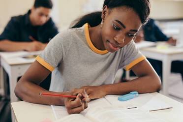 Studentin schreibt Notizen während einer Vorlesung im Klassenzimmer. Junge Frau studiert an der Universität. - JLPSF17147