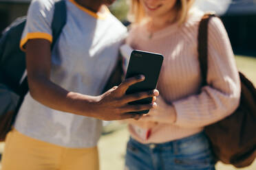 Nahaufnahme von zwei jungen Frauen, die ein Selfie mit einem Smartphone an der Universität machen. Studenten, die ein Selfie mit einem Mobiltelefon im Freien auf dem Campus machen. - JLPSF17156