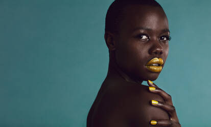 Afrikanische Frau mit lebhaftem Make-up auf den Lippen und Nägeln, weibliches Modemodell in Pose vor grauem Hintergrund. - JLPSF17171