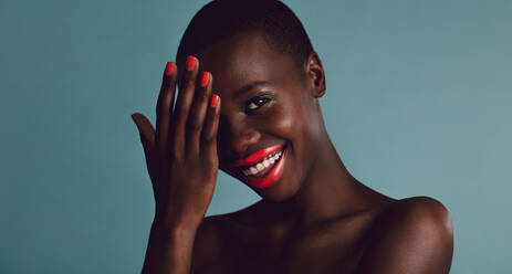 Schöne afrikanische Frau mit lebhaftem Make-up. Weibliches Modell lächelnd vor grauem Hintergrund. - JLPSF17172
