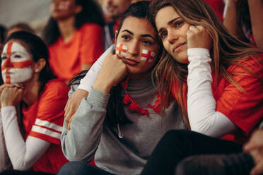 Sportfans, die nach einem verlorenen Spiel traurig dreinschauen. Enttäuschte englische Fußballfans, die sich ein Spiel im Stadion ansehen. - JLPSF17252
