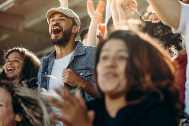 Eine Gruppe glücklicher Fans jubelt über den Sieg ihrer Mannschaft. Freunde haben Spaß, während sie sich ein Spiel im Stadion ansehen. - JLPSF17272