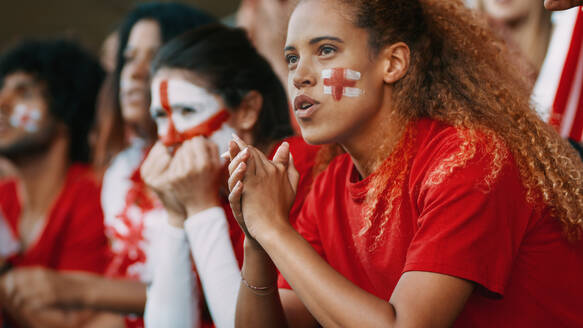 Ängstlich blickende weibliche Fußballfans, die das Spiel im Stadion verfolgen. Gruppe englischer Fußballfans, die das Spiel von der Tribüne im Stadion aus verfolgen. - JLPSF17303