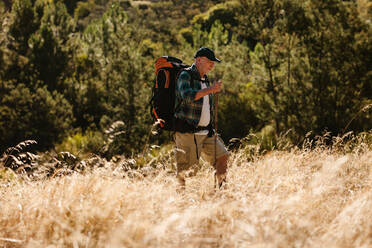 Älterer Mann, der auf einem Bergpfad wandert. Älterer Mann, der einen Rucksack beim Wandern in der Natur trägt. - JLPSF17333