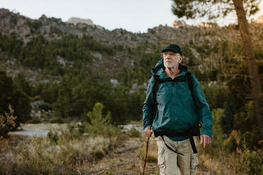 Älterer Mann, der auf einem Bergpfad wandert. Selbstbewusster reifer Mann, der einen Rucksack beim Wandern in der Natur trägt. - JLPSF17356