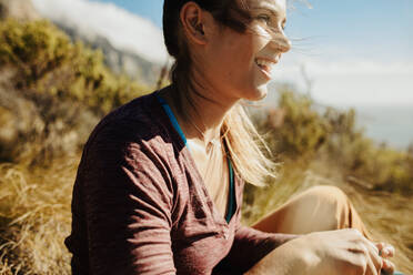 Woman hiker sitting on cliff and looking away at the view. Female mountain climber looking at the view for the top of the mountain. - JLPSF17368