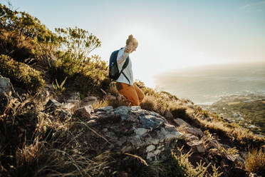 Frau mit Rucksack, die den Berg hinuntergeht. Bergsteigerin, die die Klippe hinuntergeht. - JLPSF17384