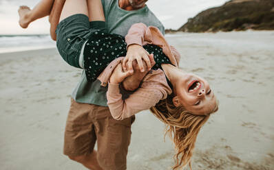 Mann trägt seine Tochter und geht am Strand spazieren. Vater und Tochter haben eine tolle Zeit am Strand Urlaub. - JLPSF17403