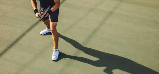 Tennisspieler, der auf einem Hartplatz Tennis spielt. Junger Mann in Sportkleidung, der auf einem harten Tennisplatz steht und bereit ist, den Aufschlag während eines Spiels zurückzugeben. - JLPSF17462
