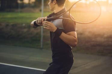 Young male tennis player returning the serve with a forehand. Tennis player playing on club hard court. - JLPSF17509