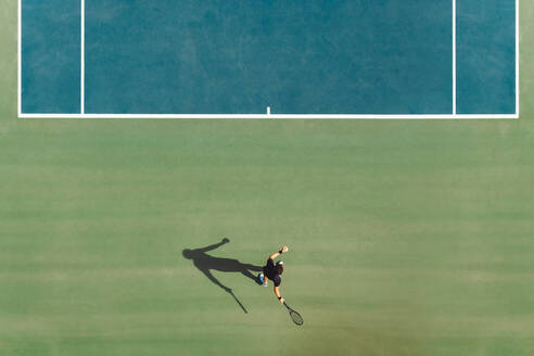 Luftaufnahme eines jungen männlichen Tennisspielers, der auf einem Hartplatz spielt. Ein professioneller Tennisspieler schlägt eine Vorhand auf dem Platz. - JLPSF17512