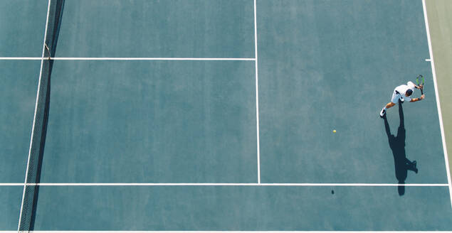 Luftaufnahme eines jungen Tennisspielers, der auf einem Hartplatz spielt. Ein professioneller Tennisspieler schlägt eine Rückhand auf dem Platz. - JLPSF17514