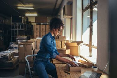 Weibliche Geschäftsinhaberin bei der Arbeit, Verpackung der Bestellung für den Versand an den Kunden. Weibliche Unternehmerin Verpackungsbox für die Lieferung. - JLPSF17578