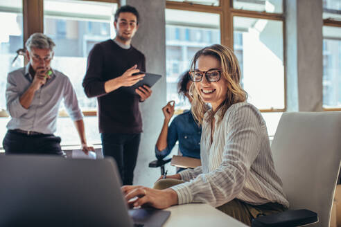 Unternehmerin, die an einem Laptop arbeitet und ihre Strategie erläutert, um Kunden für einen Online-Web-Shop zu gewinnen, während sie sich mit Kollegen im Büro trifft. - JLPSF17600