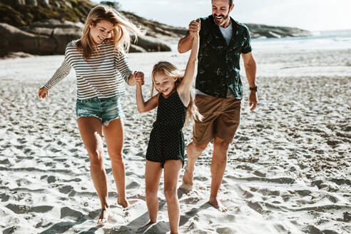 Ein Mädchen spielt mit seinen Eltern am Strand, eine dreiköpfige Familie spielt an einem Sommerwochenende am Strand. - JLPSF17607