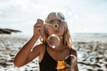 Girl blowing soap bubbles on the beach. Girl having fun on the beach. - JLPSF17610