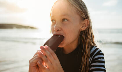 Mädchen isst gerne Eis am Strand im Sommer. Mädchen isst Eis im Sommerurlaub. - JLPSF17618