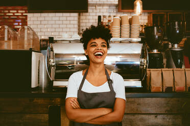 Woman barista inside her coffee shop. Woman bartender in cheerful mood standing in front on the counter. - JLPSF17643