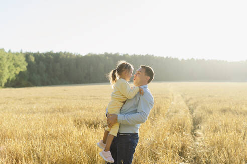 Vater trägt Tochter im Feld an einem sonnigen Tag - SEAF01382