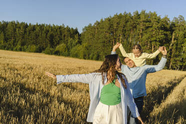 Happy mother and father enjoying with daughter in field - SEAF01396