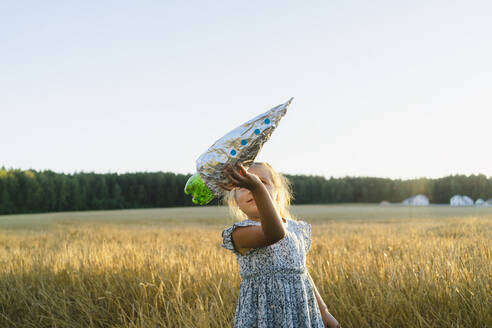 Mädchen spielt mit selbstgebauter Spielzeugrakete auf einem Feld - SEAF01419