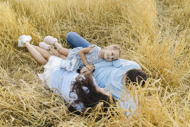 Smiling girl relaxing with father and mother amidst crops in field - SEAF01432