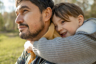 Boy embracing father from behind in park - ANAF00272