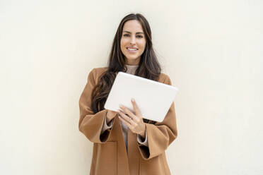 Lächelnde Frau mit Tablet-PC vor einer weißen Wand - DLTSF03313