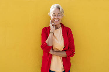 Lächelnde reife Frau vor einer gelben Wand - OIPF02464