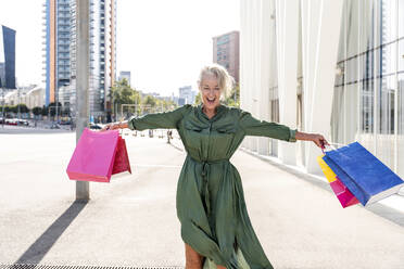 Glückliche Frau mit Einkaufstaschen an einem sonnigen Tag - OIPF02495