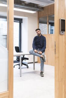 Junger Geschäftsmann sitzt am Schreibtisch im Büro - JAQF01087