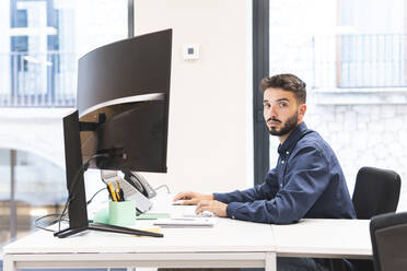 Businessman sitting at desk in office - JAQF01090