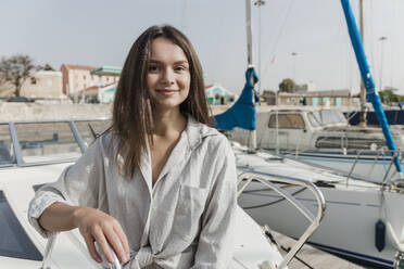 Lächelnde junge Frau auf einem Boot sitzend - JRVF03137