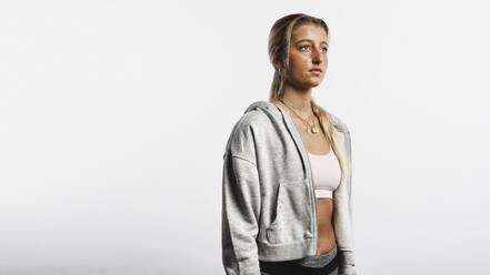 Porträt von Fitness-Frau vor weißem Hintergrund. Lächelnde Frau Athletin schaut weg. - JLPSF17791