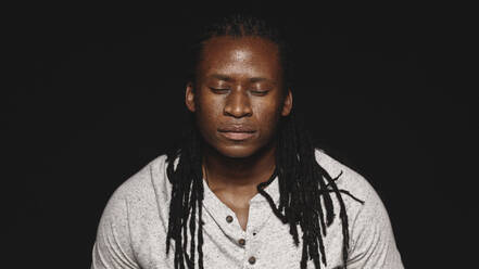Afrikanischer Mann mit Dreadlocks isoliert auf schwarzem Hintergrund, Portrait eines Mannes mit geschlossenen Augen. - JLPSF17831