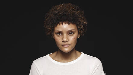 Portrait of a young woman isolated on black background. Woman with curly hair looking at camera. - JLPSF17848